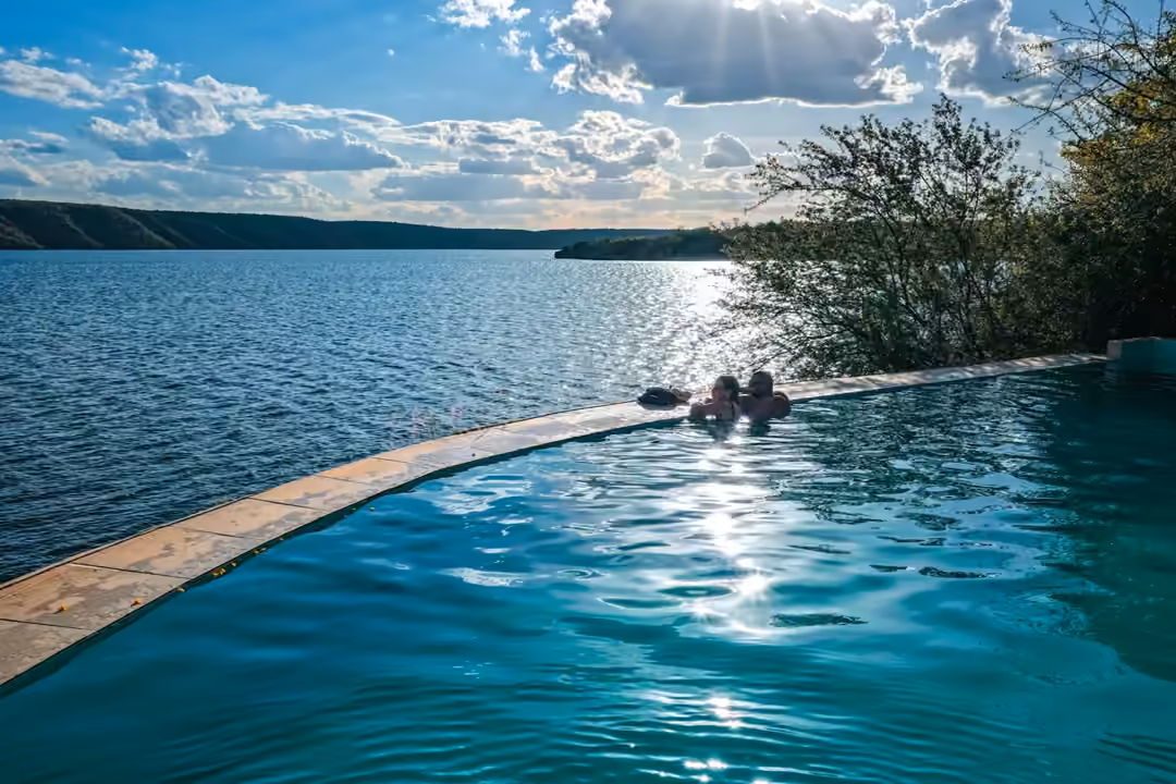 Piscina de borda infinita com o sol refletido no Rio São Francisco