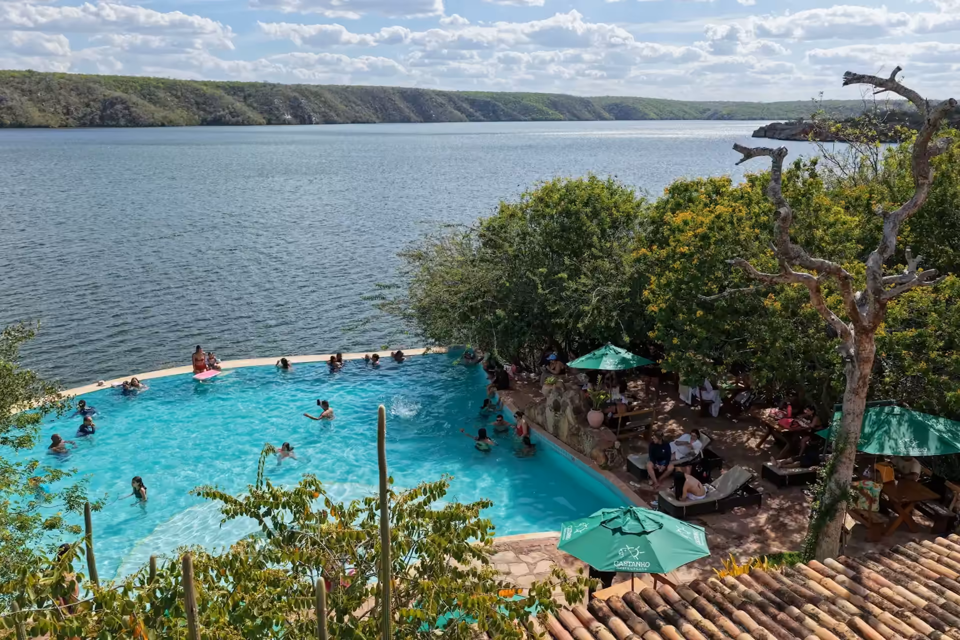 Piscina de borda infinita e mesas do Restaurante Castanho diante do Rio São Francisco