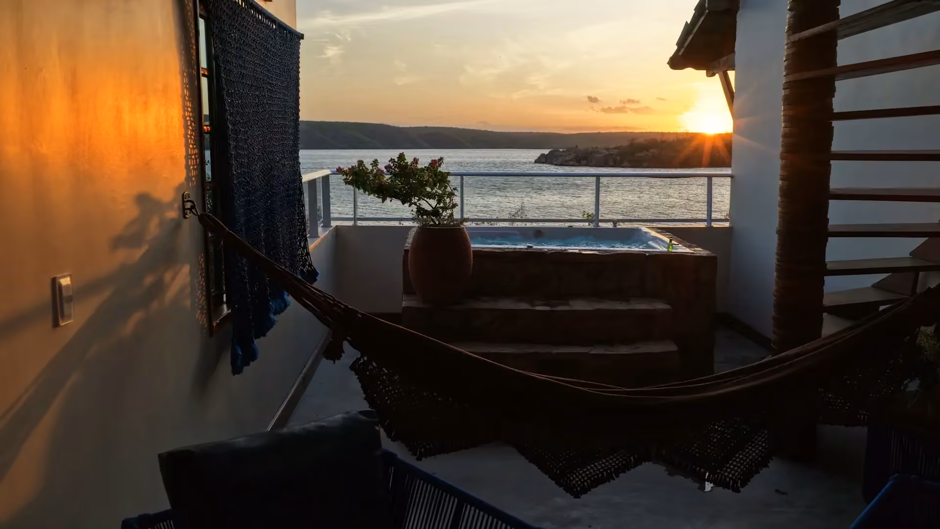 Varanda com rede e banheira ao pôr do sol sobre o Velho Chico